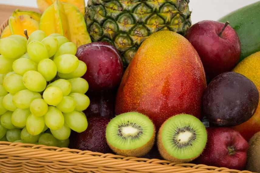 Mixed fruit in a cane basket. Grapes, plums, kiwi, mango, apples, pineapple and star fruit.