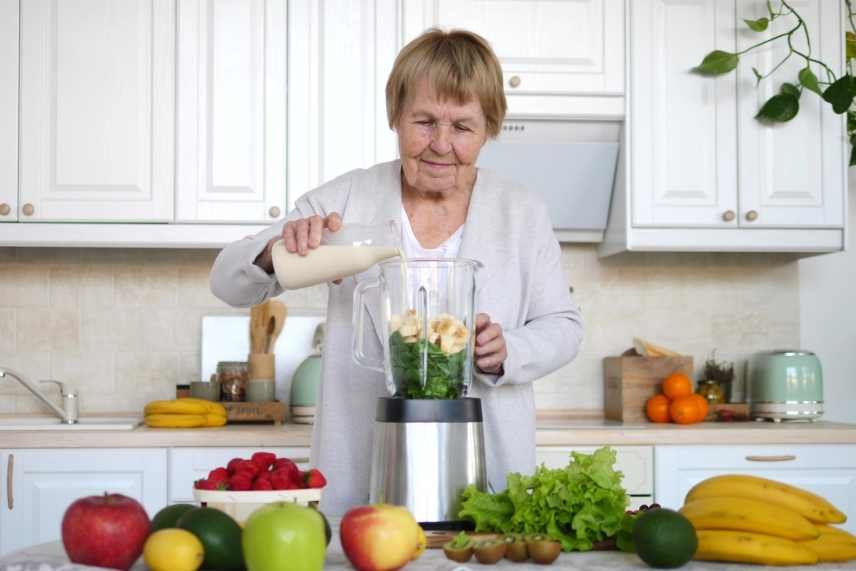 Image of an elderly woman making a smoothie depicting the evolution of smoothies.