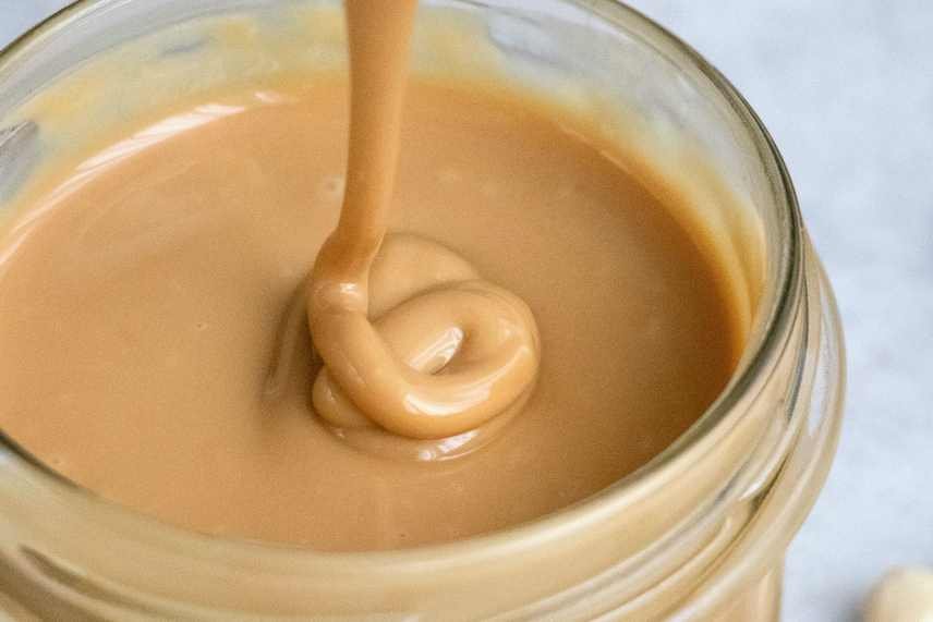 A closeup shot of a jar of almond butter, a key ingredient in making a Almond Joyous Chocolate Smoothie.