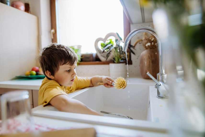 An image of a young boy doing the dishes, depicting how easy it is to clean a Nutribullet Personal Blender.