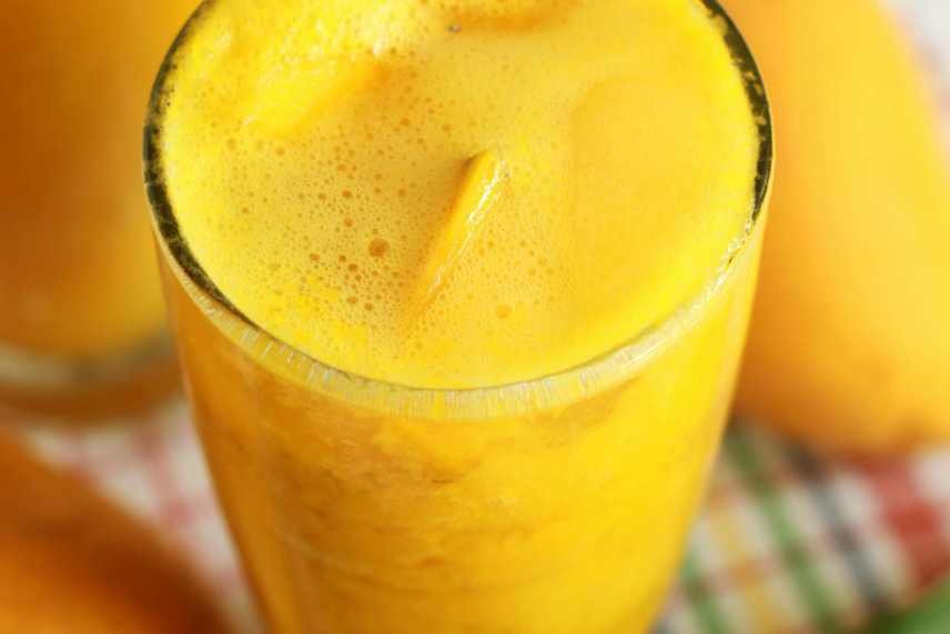 A closeup image of a Mango Pineapple Smoothie, with chunks of mango floating at the top.