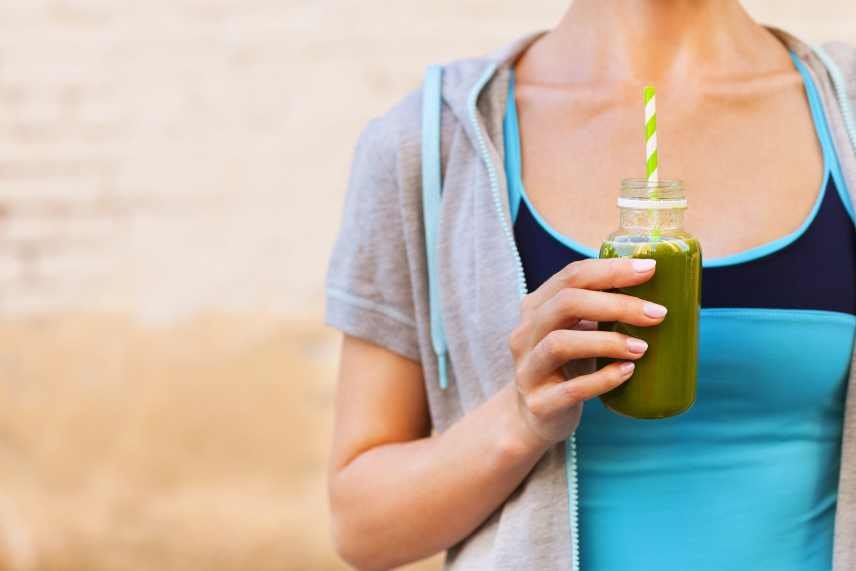 A slim, fit, woman drinking a green smoothie for energy and weight loss.